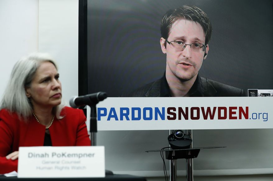 Dinah PoKempner, general council for Human Rights Watch, listens Wednesday in New York as Edward Snowden speaks on a television screen via video link from Moscow during a news conference to call upon President Obama to pardon Snowden before he leaves office. (Associated Press)