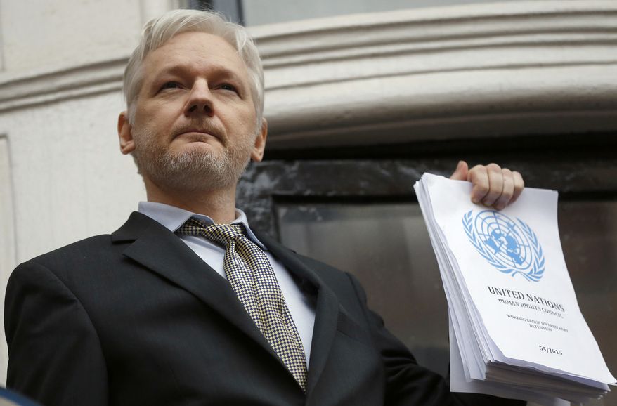 Julian Assange holds a U.N. report as he speaks on the balcony of the Ecuadorian Embassy in London in this Feb. 5, 2016  file photo. (AP Photo/Frank Augstein, File)