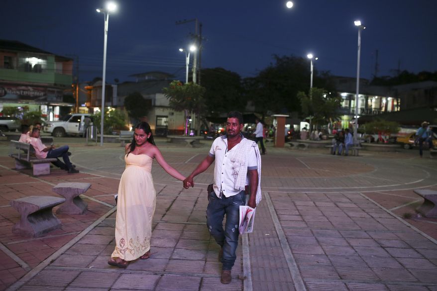 A couple walks along a park in San Vicente del Caguan, southern Colombia, Thursday, Sept. 15, 2016. Fifteen years after negotiations with leftist rebels collapsed in a fury of violence, the road to peace in Colombia once again passes through this remote southern village near where leaders of the Revolutionary Armed Forces of Colombia are gathering in a jungle conclave for their last meeting as an armed insurgency. (AP Photo/Ricardo Mazalan)