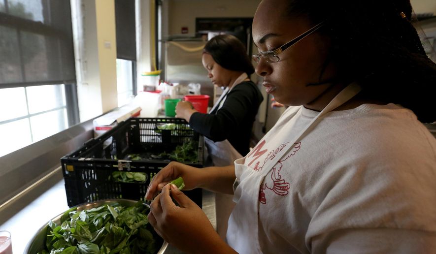 In this Wednesday, July 6, 2016 photo, Ivanah Atkinson, of Sun Prairie, peels basil during a teen employment program at the Goodman Community Center in Madison, Wis. (Michelle Stocker /The Capital Times via AP)