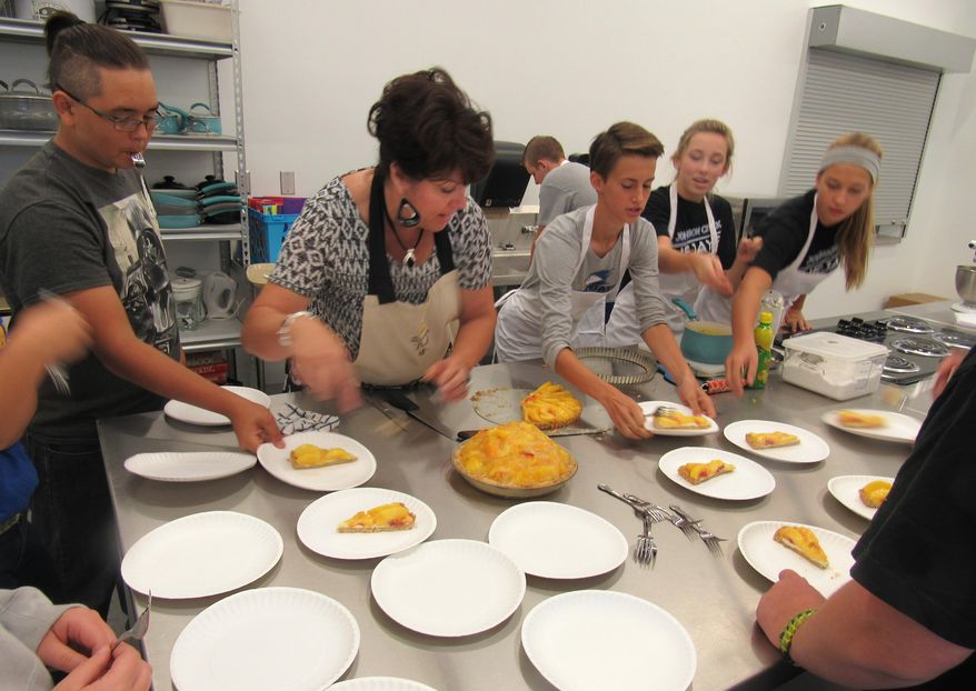 Sandy Winter, the family and consumer education teacher at Johnson Creek High School, serves up a piece of peach cobbler on Sept. 8, 2016 in Johnson Creek, Wis. Winter's room includes commercial kitchen equipment and large counters, and is adjacent to the school's cafetorium. The room is part of the newly opened $18.9 million school that is housed under a series of five domes. (Barry Adams/Wisconsin State Journal via AP)