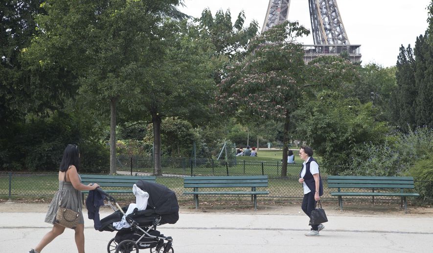 People stroll in the Champ de Mars garden near the Eiffel Tower, beside the spot where a woman was allegedly raped earlier this week, in Paris, Friday, Sept. 16, 2016. Three Algerian young men have been arrested in Paris under suspicion of raping a woman near the Eiffel Tower, according to a police official. One of the suspects chatted with her on Facebook days earlier and gave her an appointment. (AP Photo/Michel Euler)