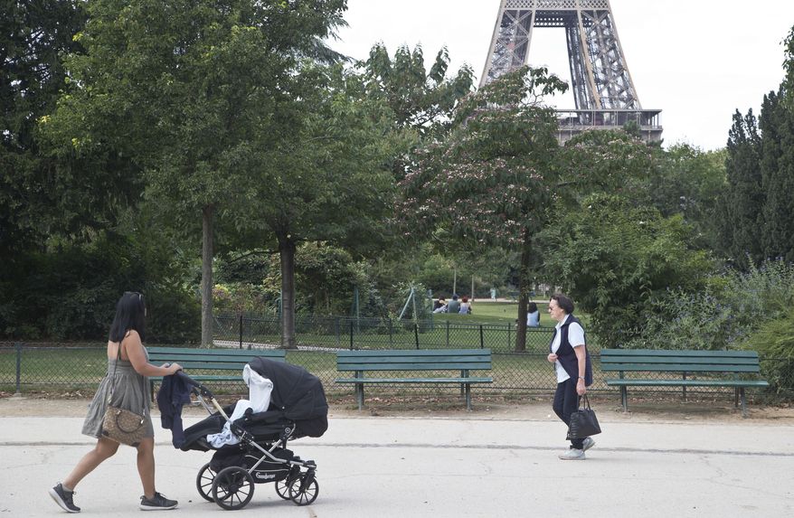 People stroll in the Champ de Mars garden near the Eiffel Tower, beside the spot where a woman was allegedly raped earlier this week, in Paris, Friday, Sept. 16, 2016. Three Algerian young men have been arrested in Paris under suspicion of raping a woman near the Eiffel Tower, according to a police official. One of the suspects chatted with her on Facebook days earlier and gave her an appointment. (AP Photo/Michel Euler)