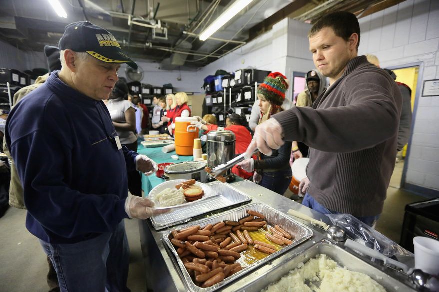 FILE - In this Dec. 25, 2013, file photo, Mike Steingold, left, of Huntington Woods, left, fills a plate with help of Cody Muirhead, of Milford, as they serve Christmas breakfast to the needy in Detroit as part of Mitzvah Day, where people from the Jewish, Christian and Muslim communities volunteer at sites around the city. The Christmas project has expanded to an event Sunday, Sept. 18, 2016, when more than 100 Muslims and Jews will fix up a struggling Detroit school. (Kimberly P. Mitchell/Detroit Free Press via AP, File)   /Detroit Free Press via AP)