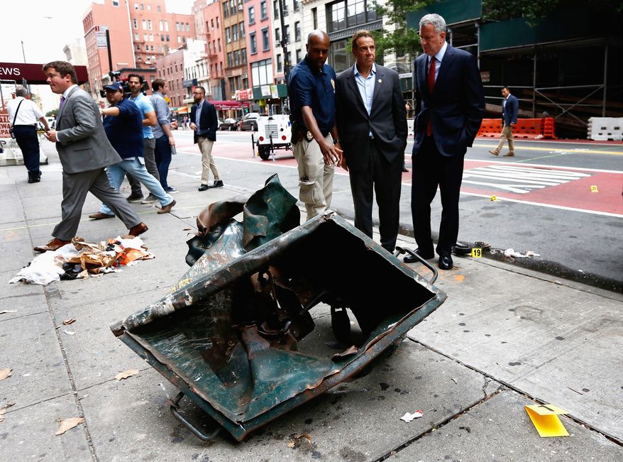 New York Mayor Bill de Blasio (right) and New York Gov. Andrew Cuomo (center) looked over a mangled construction toolbox on Sunday while touring the site of an explosion on Saturday night that injured 29 people. (Associated Press)