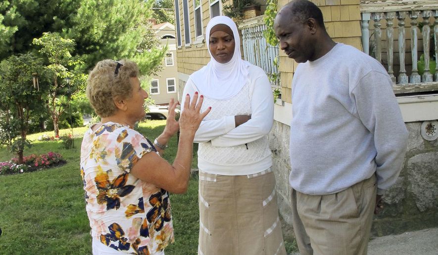 In this Sept. 16, 2016 photo, Fresh Start translator Samira Clough, left, speaks to Amna Salim Ali, center, and her husband Ezairig El Nemair in front of their home in New London, Conn. The Sudanese couple are among about 500 refugees being resettled this year by Integrated Refugee & Immigrant Services with the help of community organizations across the state. (AP Photo/Pat Eaton-Robb)