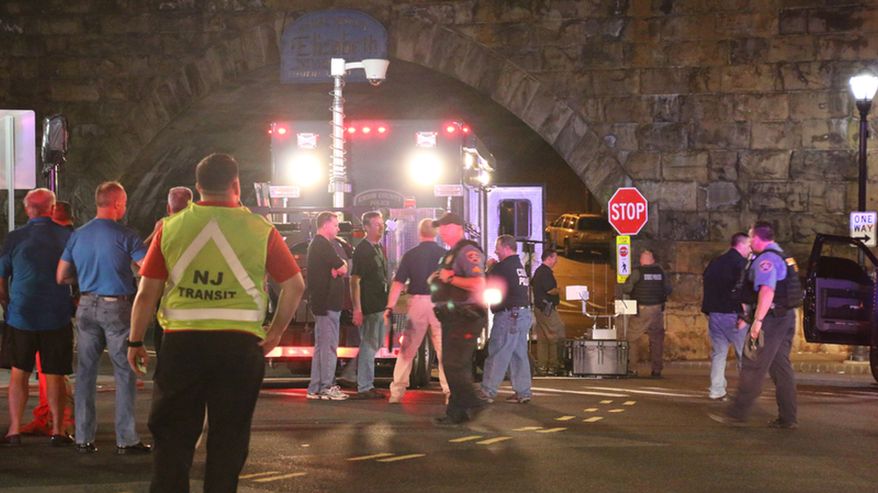 Bomb squad personnel stand around the scene of an explosion near the train station early Monday, Sept 19, 2016, in Elizabeth, New Jersey. A suspicious device found Sunday night in a trash can near a New Jersey train station exploded early Monday as a bomb squad robot attempted to disarm it. (Jessica Remo/ NJ Advance Media for NJ.com via AP)