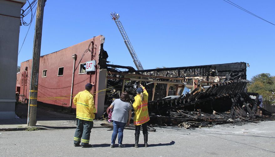 In this photo taken Sunday, Sept. 18, 2016, and provided by the Half Moon Bay Review, fire officials look over the remains of the Pescadero Country Store that burned to the ground in Pescadero, Calif. A fire destroyed the popular watering hole for residents and tourists of Northern California's coastal region early Sunday morning. No injuries were reported, but the small coastal town 50 miles south of San Francisco lost a community hub where local gathered for special occasions and frequented by tourists traveling along Highway 1. (Carina Woudenberg/Half Moon Bay Review via AP)