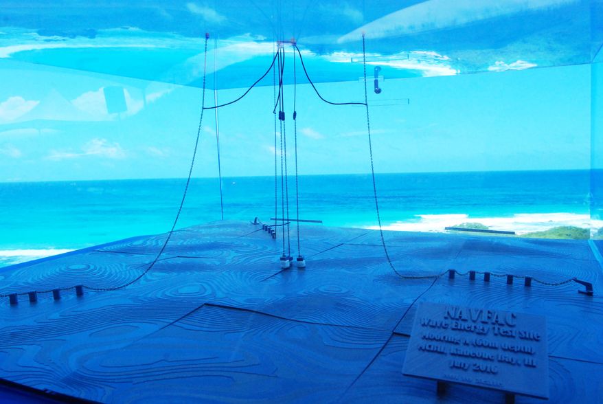In this July 26, 2016 photo, a model of a wave energy test site at Kaneohe Bay on Oahu in Hawaii shows undersea cables that hold machinery in place. The cables in the middle move up and down with the waves, turning the wheels of generators in the donut-shaped Lifesaver device, which is deployed at the Navy's Wave Energy Test Site at the Marine Corps base at Kaneohe Bay on Oahu in Hawaii. By some estimates, the ocean's endless motion packs enough power to meet a quarter of America's energy needs and dramatically reduce the nation's reliance on oil, gas and coal. But wave energy technology lags well behind wind and solar power. (AP Photo/Cathy Bussewitz)