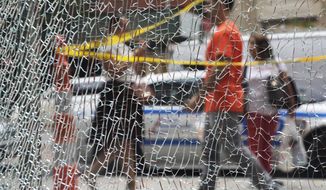 New Yorkers pass a shattered storefront window on W. 23rd St. in Manhattan, Tuesday, Sept. 20, 2016, in New York. The window was hit by shrapnel from the terrorist bomb that exploded across the street Saturday evening. An Afghan immigrant wanted in the bombings was captured Monday after being wounded in a gun battle with police. (AP Photo/Mark Lennihan)