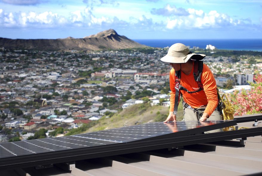 FILE - In this Friday, July 8, 2016, file photo, Dane Hew Len, lead installer for RevoluSun, places a solar panel on a roof in Honolulu. The Hawaii Public Utilities Commission approved a plan for Hawaiian Electric's customers to enroll in a program that charges different rates for electricity based on the time of day. Solar advocates have pushed for such a program. (AP Photo/Cathy Bussewitz,File)