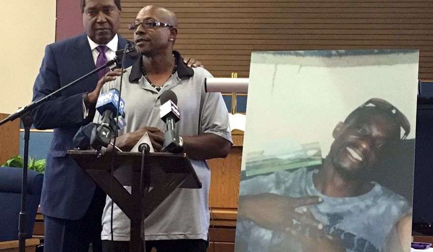 FILE - In this Aug. 5, 2016, file photo, Robert Mann Sr., right, addresses community members and reporters at Allen Chapel AME Church in Sacramento, Calif., accompanied by attorney John Burris. Displayed at right is a photo of Mann’s brother, Joseph Mann, who was shot and killed by Sacramento police in July. Sacramento police are releasing more details about the fatal police shooting this summer of a homeless man, including police dash-cam videos of the incident. Police Chief Sam Somers revealed Tuesday, Sept. 20, 2016, that officers fired 18 shots, 14 of which struck 50-year-old Joseph Mann during the July 11 incident. (AP Photo/Darcy Costello, File)
