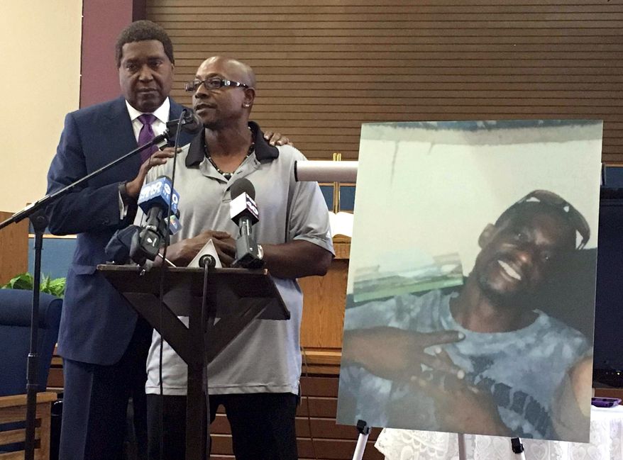 FILE - In this Aug. 5, 2016, file photo, Robert Mann Sr., right, addresses community members and reporters at Allen Chapel AME Church in Sacramento, Calif., accompanied by attorney John Burris. Displayed at right is a photo of Mann’s brother, Joseph Mann, who was shot and killed by Sacramento police in July. Sacramento police are releasing more details about the fatal police shooting this summer of a homeless man, including police dash-cam videos of the incident. Police Chief Sam Somers revealed Tuesday, Sept. 20, 2016, that officers fired 18 shots, 14 of which struck 50-year-old Joseph Mann during the July 11 incident. (AP Photo/Darcy Costello, File)