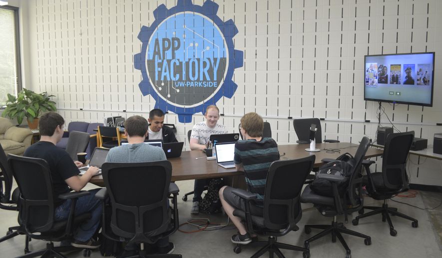 ADVANCE FOR USE MONDAY, SEPT. 26 - In this Sept. 13, 2016 photo, University of Wisconsin-Parkside students sit at the main table inside the App Factory while working on various projects in Kenosha, Wis. (Ricardo Torres/The Journal Times via AP)