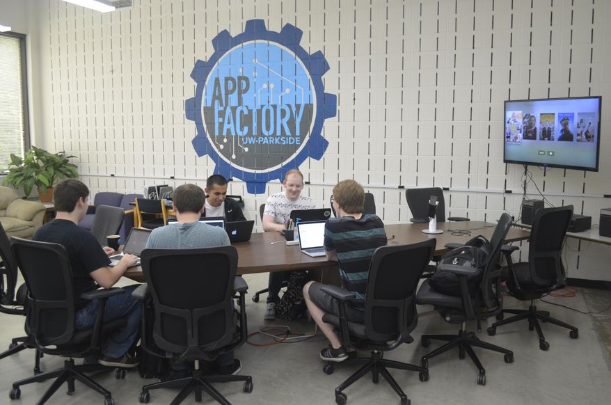 ADVANCE FOR USE MONDAY, SEPT. 26 - In this Sept. 13, 2016 photo, University of Wisconsin-Parkside students sit at the main table inside the App Factory while working on various projects in Kenosha, Wis. (Ricardo Torres/The Journal Times via AP)