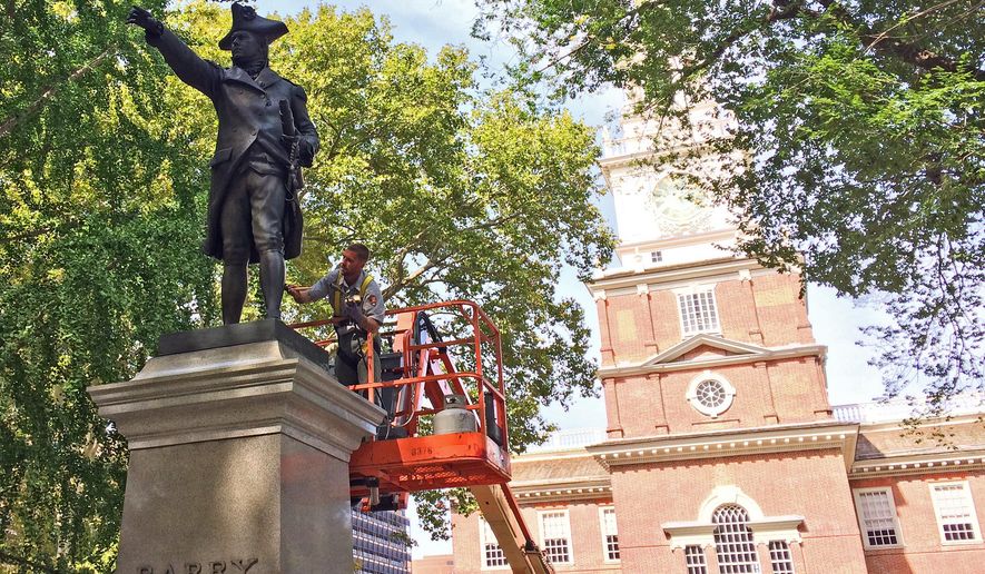Ryan Neill, a National Park Service employee from Gettysburg National Military Park, brushes wax onto a statue of U.S. Navy Commodore John Barry on Wednesday, Sept. 21, 2016, outside Independence Hall in Philadelphia. Sculptor Samuel Murray's much-photographed bronze statues of George Washington and Commodore John Barry outside Philadelphia's Independence Hall will shine brighter after their September 2016 cleaning, which the National Park Service says is required about every five years. (AP Photo/Kristen De Groot)