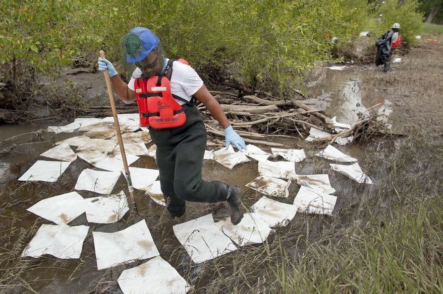 FILE - In this July 11, 2011, file photo, an oil spill crew worker for Oil Mop Emergency Response steps out of a ring of absorbent pads along a flood plain of the Yellowstone River where oil was found collected, near Laurel, Mont. Exxon Mobil Corporation has agreed to pay about $12 million for damages caused by the 2011 pipeline break that spilled gallons of crude into Montana's Yellowstone River, officials said Wednesday, Sept. 21, 2016. (AP Photo/Julie Jacobson, File)