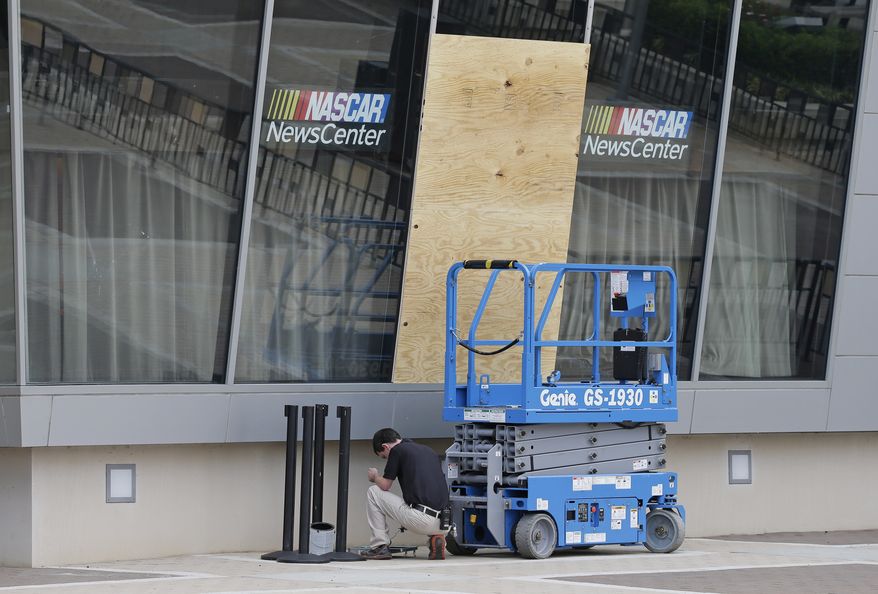 A plywood board cover a broken glass panel at the NASCAR Hall of Fame after a second night of violence following Tuesday's fatal police shooting of Keith Lamont Scott in Charlotte, N.C. Thursday, Sept. 22, 2016. (AP Photo/Chuck Burton)