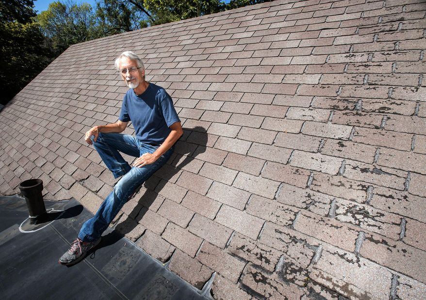 ADVANCE FOR USE SATURDAY, SEPT. 24, 2016 AND THEREAFTER - In this Sept. 12, 2016 photo, Urbana alderman Dennis Roberts sits on the roof of his home in Urbana, Ill. He is one of dozens of people he knows of locally who had home insurers tell them they would have to put new roofs on their homes when they weren't needed yet, and without much time to get the job done, or their coverage would be cancelled. (Rick Danzl/The News-Gazette via AP )