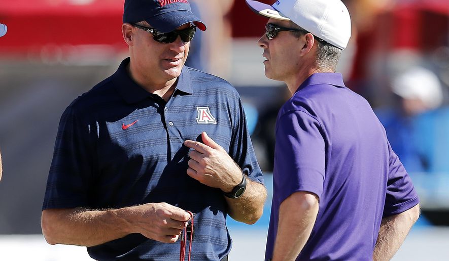 FILE - In this Nov. 15, 2014, file photo, Arizona head coach Rich Rodriguez, left, and Washington head coach Chris Petersen talk before an NCAA college football game in Tucson, Ariz. The Huskies get their first true test on Saturday against Arizona, after opening the season with three straight wins. (AP Photo/Rick Scuteri, File)