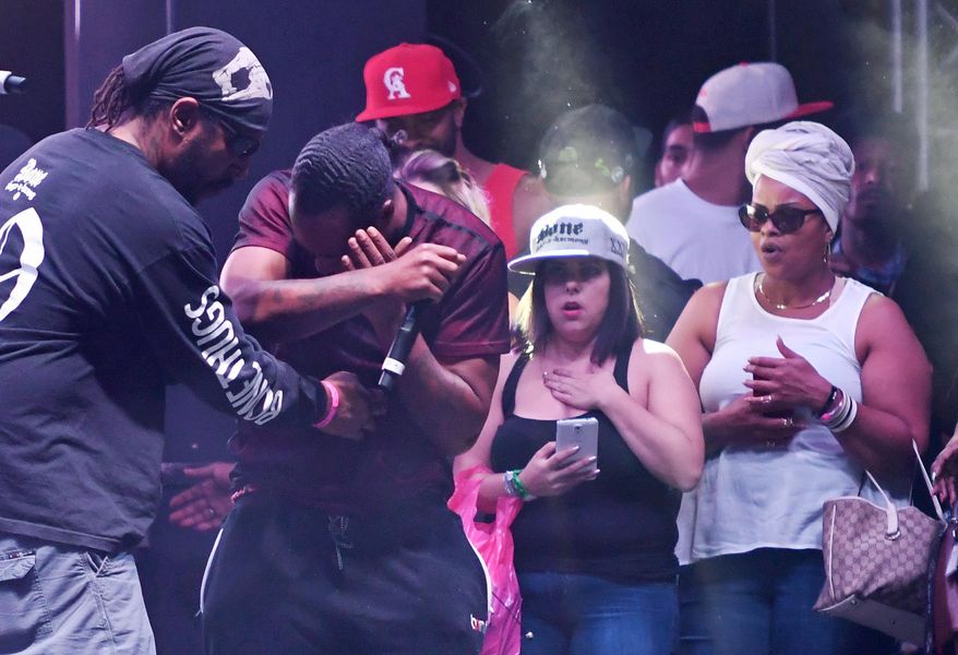 In this Sunday, Sept. 25, 2016, photo, Stanley “Flesh-N-Bone” Howse, of Bone Thugs-n-Harmony, center left, covers his face after he was hit with a drone onstage while performing during the High Life Music Festival in Victorville, Calif. (David Pardo/The Daily Press via AP)