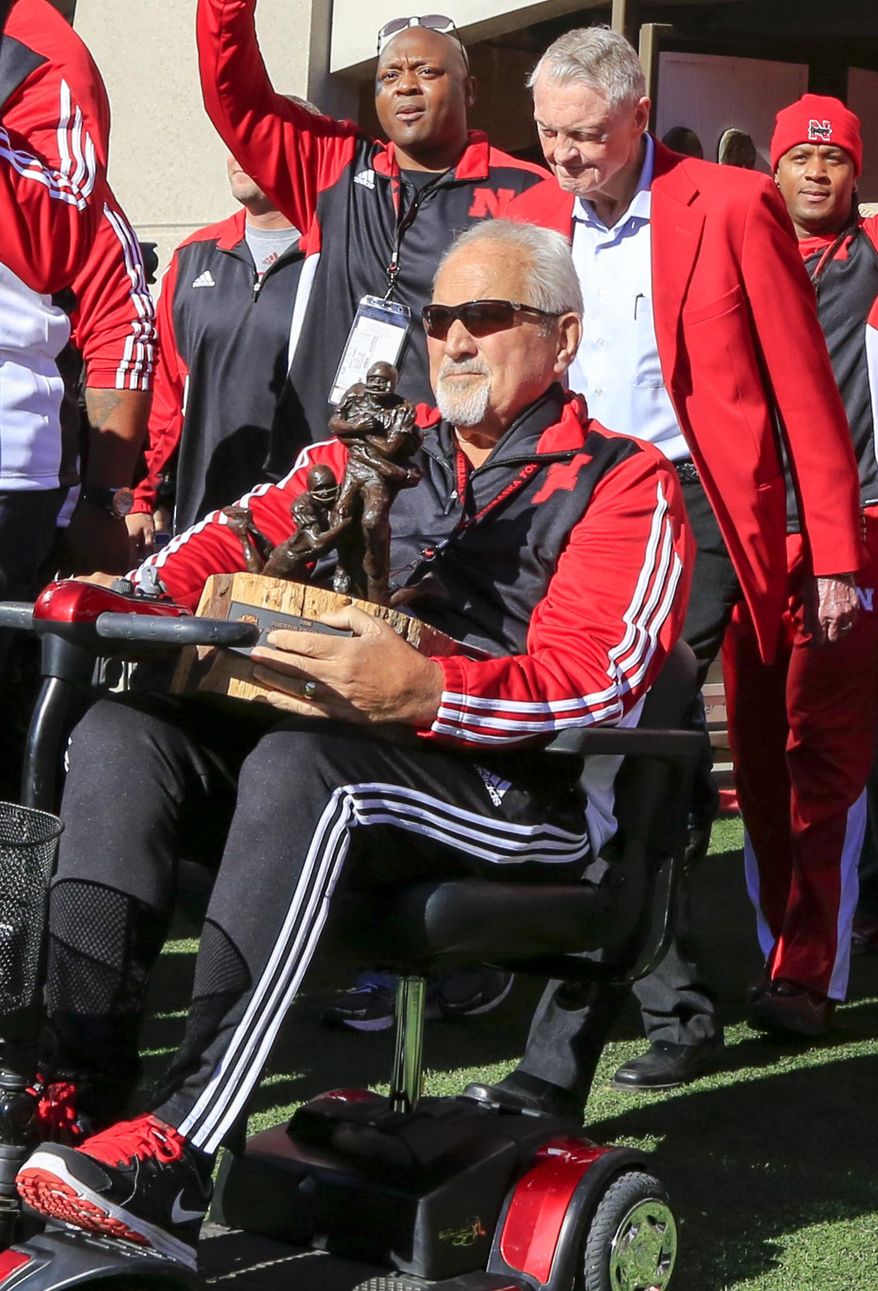 In this Oct. 24, 2015, photo, former Nebraska offensive line coach Milt Tenopir holds the 1996 Tostitos Fiesta Bowl trophy before an NCAA college football game against Northwestern, in Lincoln, Neb. Tenopir, who coached some of college football's most dominant offensive lines with Nebraska in the 1980s and '90s, has died after a long battle with cancer. He was 76. Tenopir's daughter, Kim Lester, confirmed Tenopir's death Monday, Sept. 26, 2016. Tenopir, who retired in 2003, was considered a guru of line play during his 29 years with the Cornhuskers. (AP Photo/Nati Harnik)