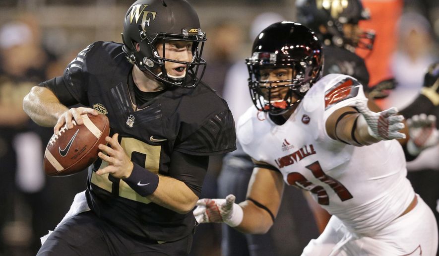FILE - In this Oct. 30, 2015, file photo, Wake Forest's John Wolford, left, scrambles away from Louisville's Trevon Young, right, in the first half of an NCAA college football game in Winston-Salem, N.C. There’s a surprise team joining No. 3 Louisville and No. 5 Clemson in the three-way tie atop the ACC's Atlantic Division, Wake Forest. Unranked but still undefeated, the Demon Deacons (4-0) are off to their best start in a decade. (AP Photo/Chuck Burton, File)