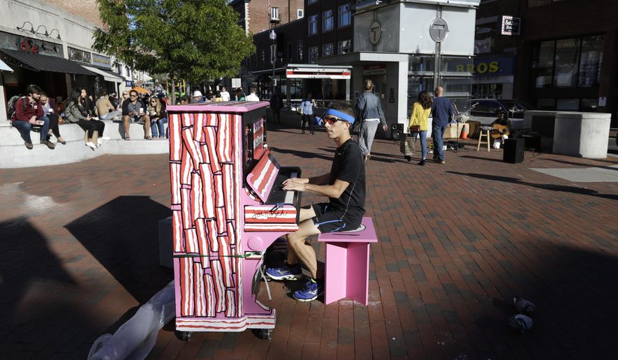 In this Sunday, Sept. 25, 2016 photo Scott Frazer, of Medford, Mass., plays a piano on the sidewalk in the Harvard Square neighborhood of Cambridge, Mass. A number of working pianos painted by local artists have been placed around Boston and Cambridge, each with a simple message to passersby: "Play Me, I'm Yours." (AP Photo/Steven Senne)