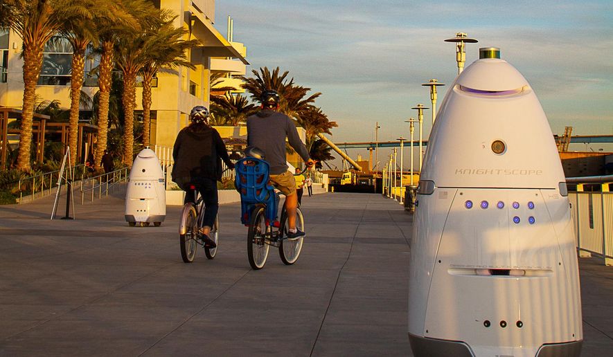 In this April 19, 2016, photo, provided by Stacy Dean Stephens, Knightscope K5 security robots, at right, and background left, patrol alongside a pier, in San Diego. The robots can identify a vehicle parked in a certain location for too long or sense intruders at odd hours. The company expects to have several large mall developers in California start using the robots in late 2016. (Stacy Dean Stephens via AP)