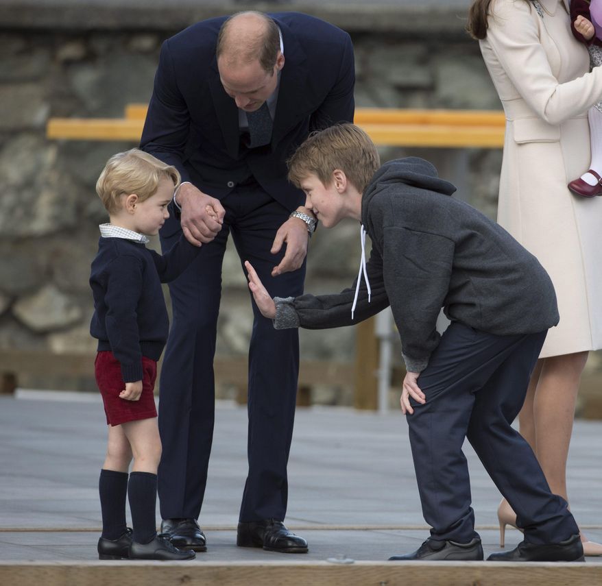Flower boy Daniel Brachman tries to give Britain's Prince George a high five as Prince William, the Duke of Cambridge, and Kate, the Duchess of Cambridge look on prior to the Royal family boarding a float plane to depart Victoria, British Columbia, Canada, on Saturday, Oct. 1, 2016. (Jonathan Hayward/The Canadian Press via AP)