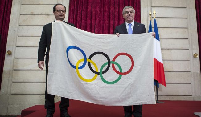 French President Francois Hollande, left, poses with International Olympic Committee President Thomas Bach, after Bach received an Olympic flag from the 1924 Olympics games during a meeting at the Elysee Palace in Paris, Sunday, Oct. 2, 2016. Paris, which last hosted the Olympics in 1924, is competing against Budapest, Rome and Los Angeles for the games. (AP Photo/Kamil Zihnioglu, Pool)