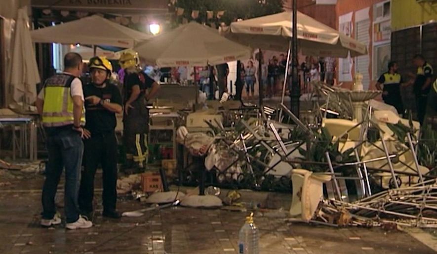 In this grab taken from video, provided by Wikono, emergency services stand outside the cafe La Bohemia, after an explosion, in Malaga, Spain, Saturday, Oct. 1, 2016. More than 70 people have been injured in a gas cylinder explosion near the southern Spanish city of Malaga, according to the local media. (Wikono via AP)