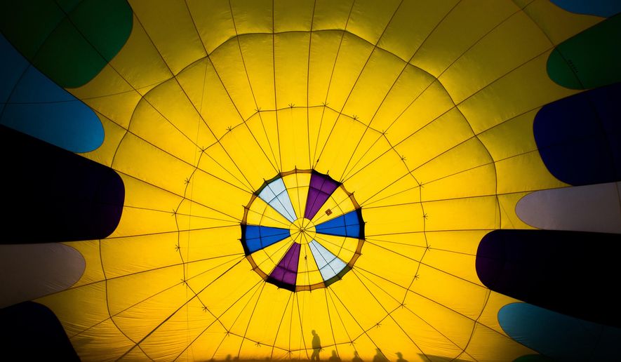 In this Friday, Sept. 23, 2016 photo, pilots, crew members and spectators gather at the airfield for the Great Prosser Balloon Rally in Prosser, Wash. McKenna Secrist’s 16th birthday in July came with a hot air balloon pilot’s license instead of a driver’s license. Secrist joined more than a dozen hot air balloon pilots at the Great Prosser Balloon Rally, where they fired up their colorful conveyances at the Prosser Airport. (Shawn Gust/Yakima Herald-Republic via AP)