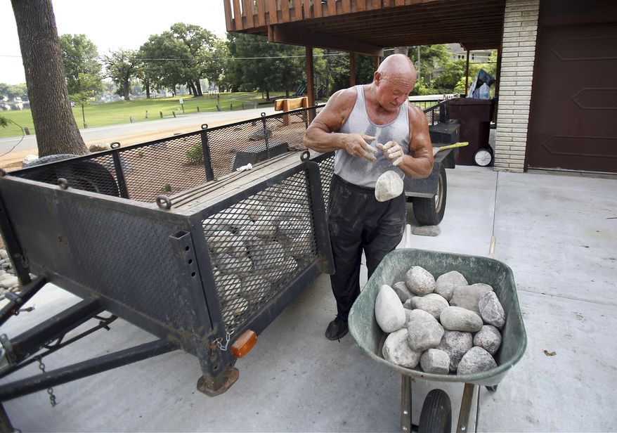 In this Sept. 7, 2016 photo, Alex Rothacker sorts through rocks as he transforms his yard into a desert, in Wildwood, Ill. He's a huge fan of the desert landscape. So much so he turned his green yard into a desert scape of rocks, gravel and cactuses. Rothacker admires the decor of the desert and describes it as clean and fresh. (Steve Lundy/Daily Herald, via AP)
