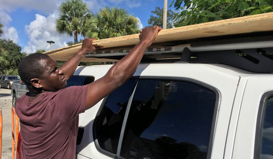 Texroy Spence, of Deerfield Beach, Fla., loads plywood onto his car at the Home Depot in Deerfield Beach, Fla. Tuesday, Oct. 4, 2016. Anxious Florida residents raided grocery store shelves and North Carolina called for the evacuation of three barrier islands as Hurricane Matthew, the most powerful Atlantic storm in a about decade, threatened to rake a large swath of the East Coast in the coming days. (Maria Lorenzino/South Florida Sun-Sentinel via AP)