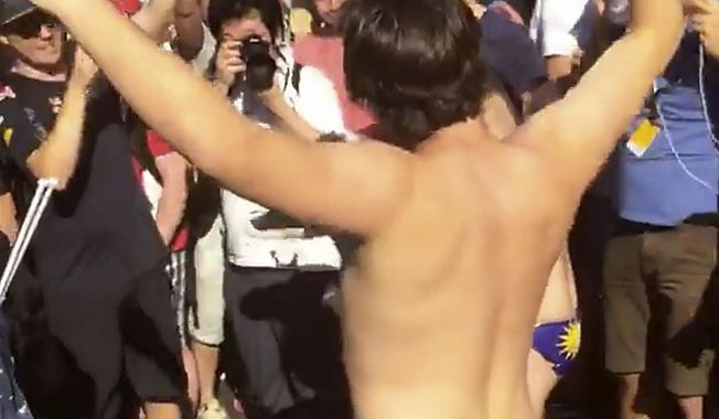 In this Sunday, Oct. 2, 2016 image made from video supplied by Umar Akif Jamaludin, an Australian man dances in Budgy Smuggler-brand swimsuits decorated with the Malaysian flag at the conclusion of the Malaysian Formula One Grand Prix in Sepang, Malaysia. Nine Australians, including a government adviser, have been arrested in Malaysia for stripping down to their briefs and drinking beer from shoes after Australian driver Daniel Ricciardo won the Malaysian Formula One Grand Prix, officials said Tuesday. (AP Photo)