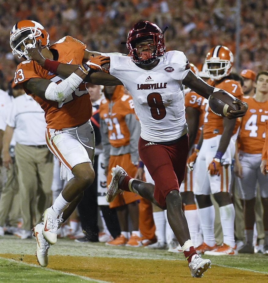 FILE - In this Oct. 1, 2016, file photo, Louisville quarterback Lamar Jackson (8) stiff-arms Clemson safety Van Smith (23) as he goes out of bounds during the second half of an NCAA college football game in Clemson, S.C. With enough games played to have a reasonable sample size, the AP begins its Heisman Watch with Jackson holding a commanding lead. (AP Photo/Rainier Ehrhardt, File)
