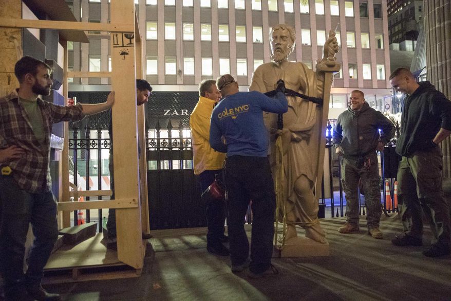 Contractors attach a resin replica of the original statue of St. Paul to a crane as they prepare to install it in the tympanum of St. Paul's Chapel, Tuesday, Oct. 4, 2016, in New York. Manhattan's oldest church is getting ready to celebrate its 250-year history, which includes worshippers ranging from George Washington to those who searched for victims following the Sept. 11 attacks. St. Paul's Chapel in Lower Manhattan is best known today as the "Little Church that Stood," having survived unscathed as the World Trade Center towers came down across the street. (AP Photo/Mary Altaffer)