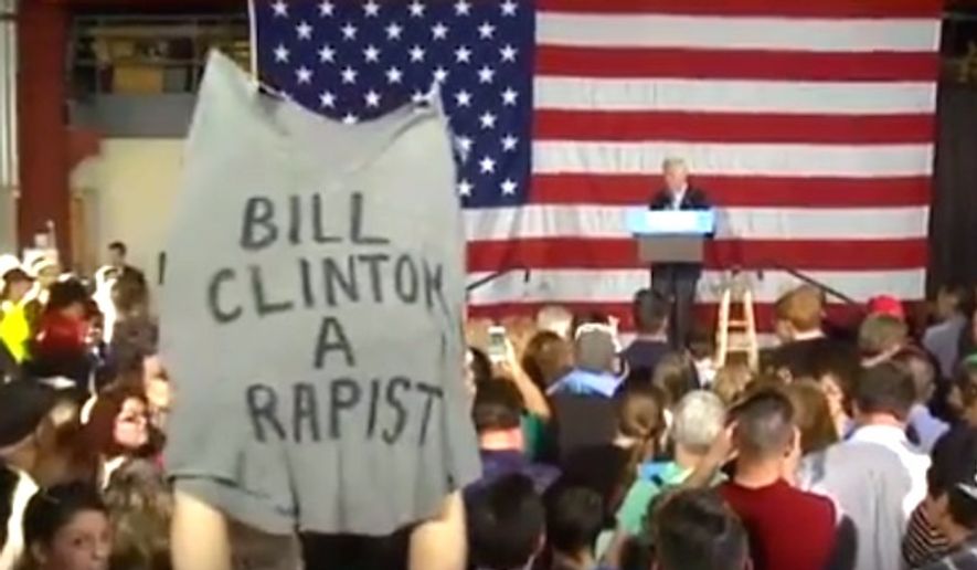 A woman holds up a shirt reading &quot;Bill Clinton is a rapist&quot; while the former president speaks in Canton, Ohio, Oct. 5, 2016. (YouTube, NTK News) 
