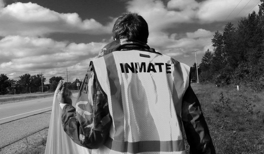 ADVANCED FOR RELEASE SATURDAY, OCTOBER 8, 2016 Keeping warm in the chilly September morning, Zachariah Reynolds, an inmate at the Portage County Jail walks along State 54 with an inmate work crew detail in Portage County, Wis., Sept. 30, 2016. (Jacob Byk/Stevens Point Journal via AP)