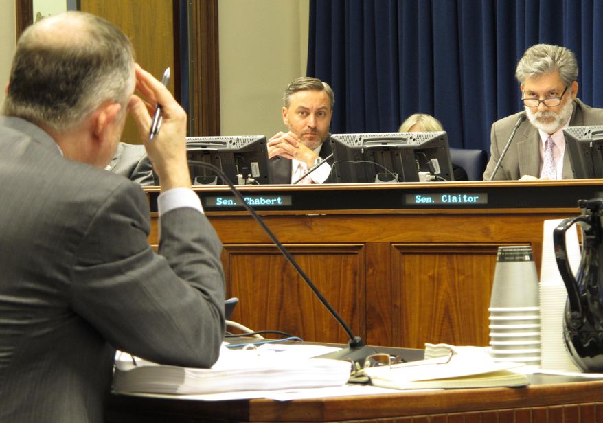 State Sen. Dan Claitor, R-Baton Rouge, right, asks questions of a state health department official about a Medicaid contract while Sen. Norby Chabert, R-Houma, left, listens during a meeting of the House and Senate health care committees, on Thursday, Oct. 6, 2016, in Baton Rouge, La. The committees agreed to a one-year, $46 million contract extension for the company that processes bills for Medicaid services. (AP Photo/Melinda Deslatte)