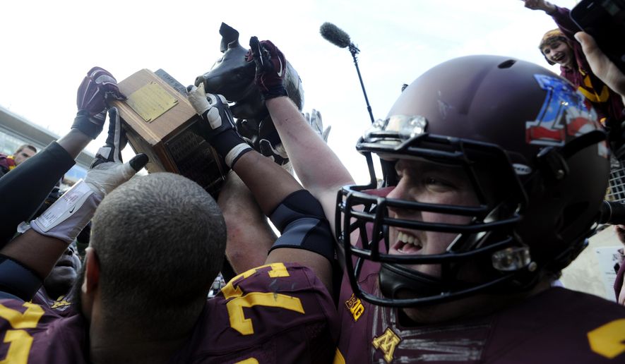 FILE - In this Nov. 8, 2014, file photo, Minnesota offensive lineman Joe Bjorklund (73) and offensive lineman Kyle McAvoy (71) hoist the Floyd of Rosedale trophy after their 51-14 win in an NCAA college football game against Iowa, in Minneapolis. Iowa at Minnesota. Floyd of Rosedale isn't all that's at stake. The loser will have virtually no room for error the rest of the way if it hopes to be a factor in the West. (AP Photo/Hannah Foslien, File)