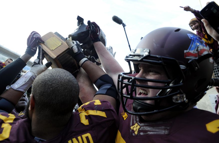 FILE - In this Nov. 8, 2014, file photo, Minnesota offensive lineman Joe Bjorklund (73) and offensive lineman Kyle McAvoy (71) hoist the Floyd of Rosedale trophy after their 51-14 win in an NCAA college football game against Iowa, in Minneapolis. Iowa at Minnesota. Floyd of Rosedale isn't all that's at stake. The loser will have virtually no room for error the rest of the way if it hopes to be a factor in the West. (AP Photo/Hannah Foslien, File)