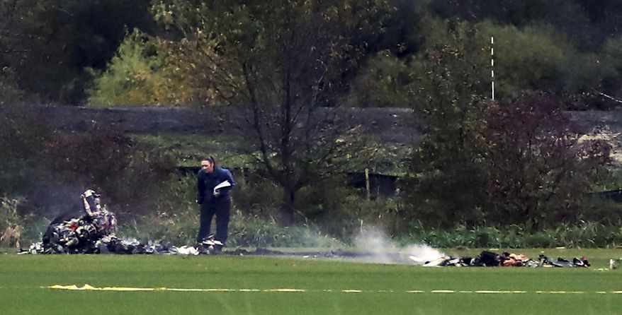 An investigator looks over the scene where a helicopter crashed in a field in Lino Lakes, Minn., on Thursday, Oct. 6, 2016. Two people died when a helicopter erupted in "a large fireball" as it crashed into a field in the Twin Cities suburb, a sheriff's official said Friday. (Richard Tsong-Taatarii/Star Tribune via AP)