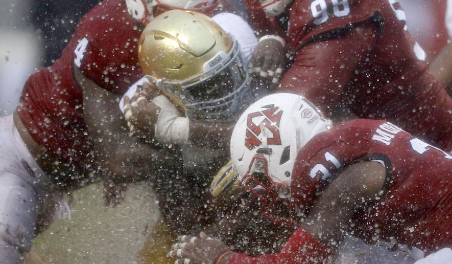 North Carolina State's Jerod Fernandez (4), B.J. Hill (98) and Jarius Morehead (31) tackle Notre Dame running back Josh Adams (33) during the first half of an NCAA college football game at Carter-Finley Stadium in Raleigh, N.C., Saturday, Oct. 8, 2016. (Ethan Hyman/The News & Observer via AP)