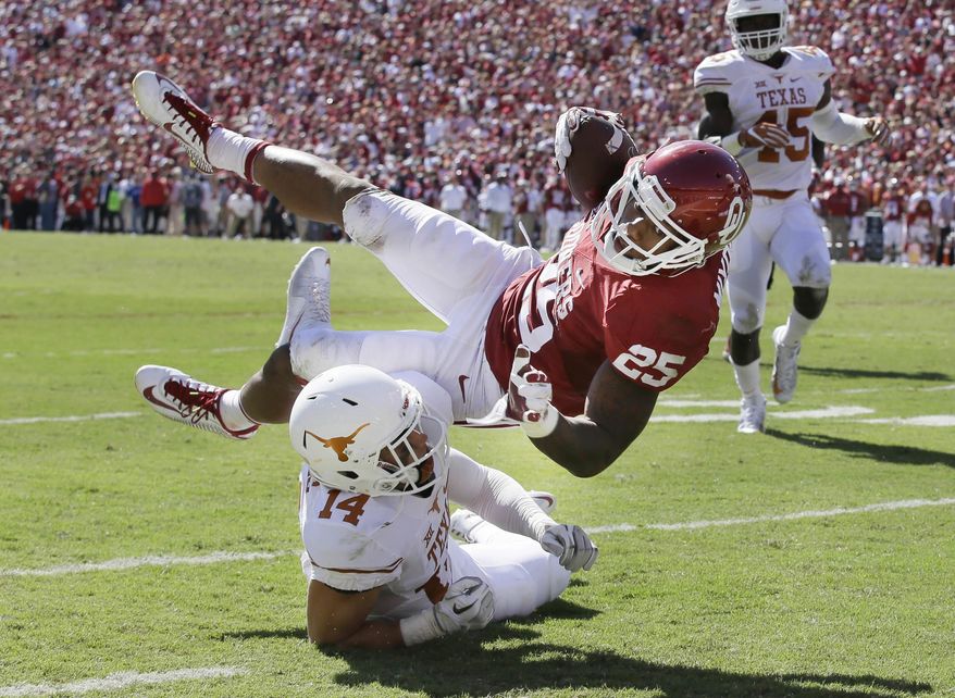 Oklahoma running back Joe Mixon (25) is knocked off his feet by Texas safety Dylan Haines (14) during the first half of an NCAA college football game in Dallas Saturday, Oct. 8, 2016. (AP Photo/LM Otero)