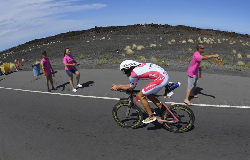 Jan Frodeno, of Germany, rides as volunteers hand out drinks during the cycling portion of the Ironman World Championship Triathlon, Saturday, Oct. 8, 2016, in Kailua-Kona, Hawaii. (AP Photo/Mark J. Terrill)