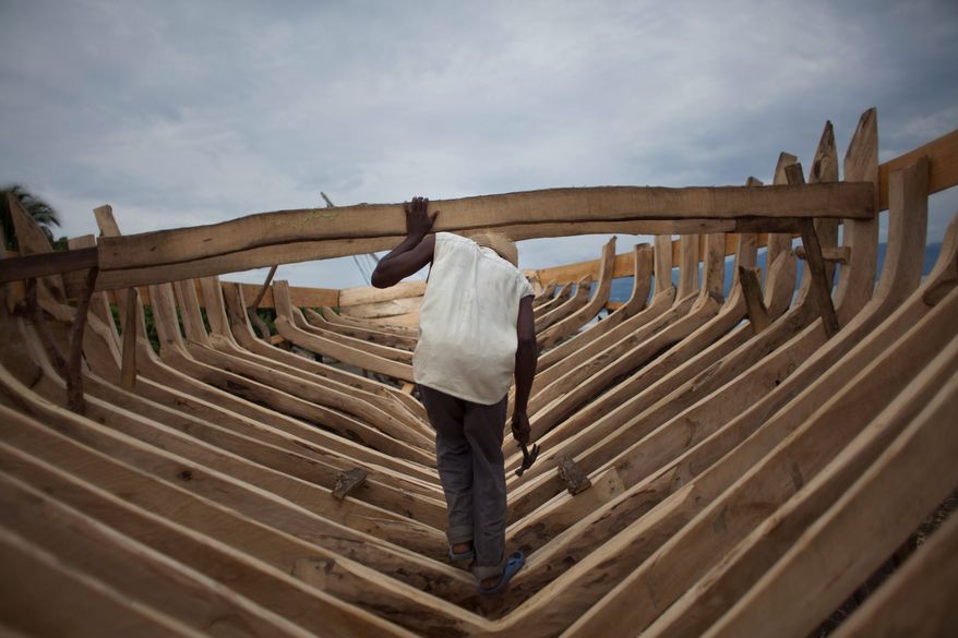 Boat maker Audit Volmar walks inside the shell of a sail boat he&#39;s building on the beach of Leogane, Haiti. The 30-foot-long boats are purchased by smugglers for around $12,000 and then taken to northern Haiti to find passengers. (Associated Press)