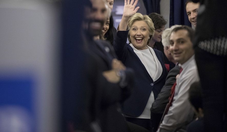 Democratic presidential candidate Hillary Clinton waves to members of the media while aboard her campaign plane at LambertSt. Louis International Airport in St. Louis, N.Y., Sunday, Oct. 9, 2016, following the second presidential debate at Washington University. (AP Photo/Andrew Harnik)