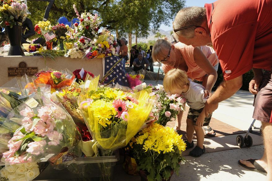 Two-year-old Jayden Bunnell kisses flowers at the urging of his grandparents Barbara Bunnell and J.D. Bunnell, from Cathedral City, Calif., for slain Palm Springs Police Officers Jose "Gil" Gilbert Vega and Lesley Zerebny, in front of the police station in Palm Springs, Calif., Sunday, Oct. 9, 2016. Vega and Zerebny, trying to resolve a family dispute, were killed Saturday when a man they had been speaking with suddenly pulled out a gun and opened fire on them, the city's police chief said. (AP Photo/Rodrigo Pena)